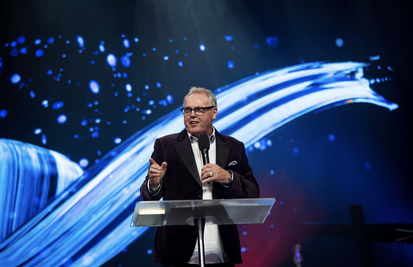 Peter Mortlock on stage in a suit