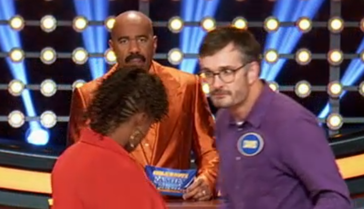 Me shooting a death stare at my opponent on Family Feud, as host Steve Harvey does his thing on the background!