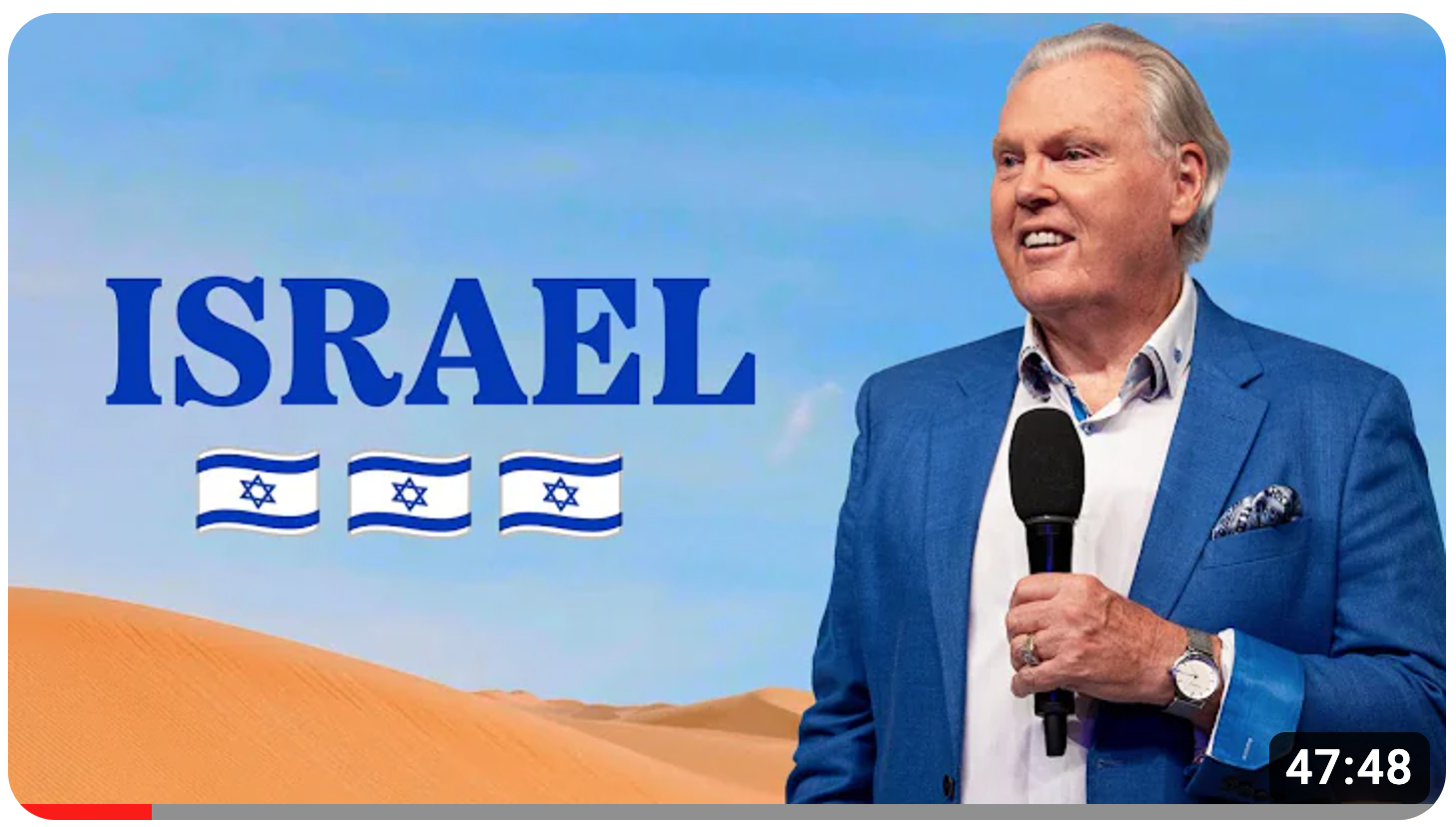 Peter Mortlock on stage some with Israeli flags behind him