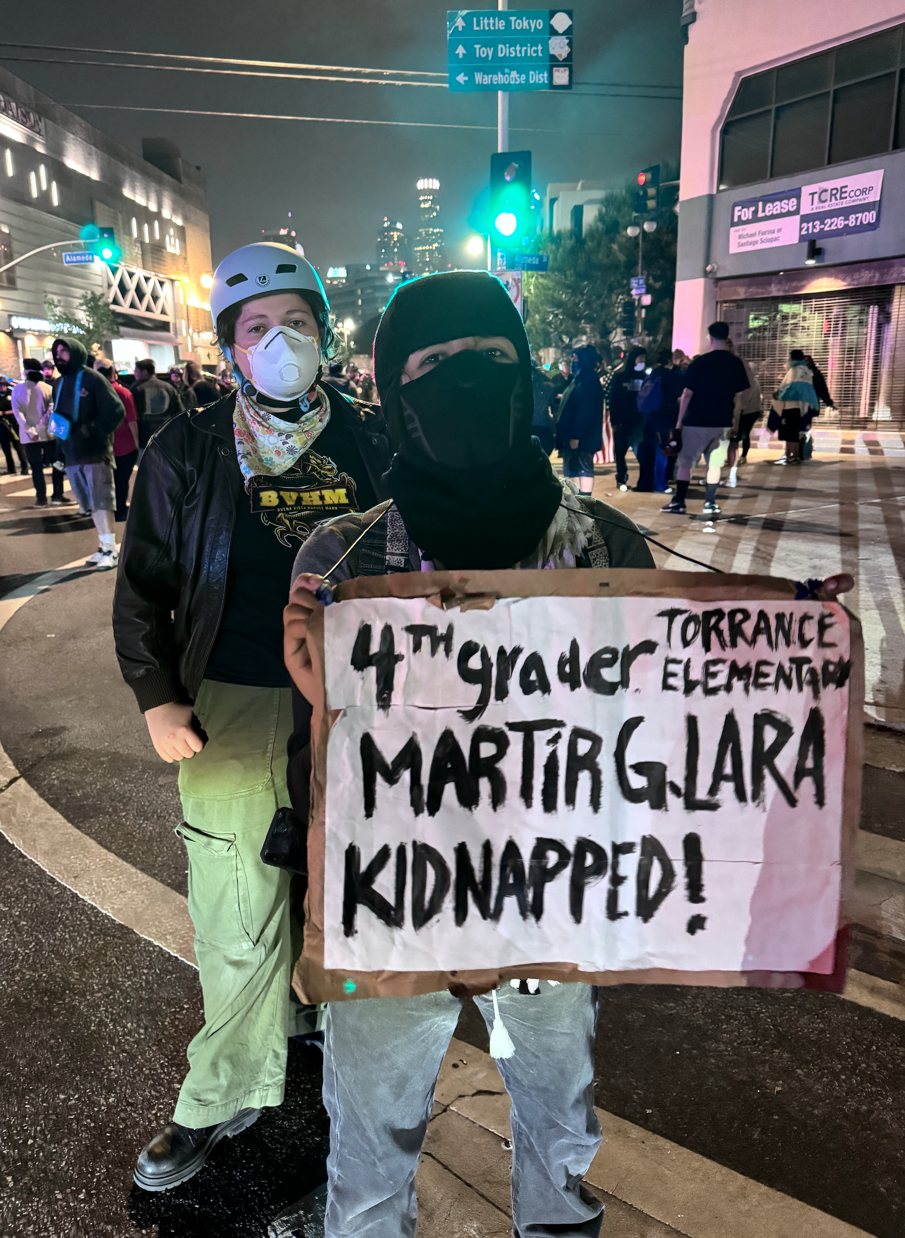 Woman holding sign, masked