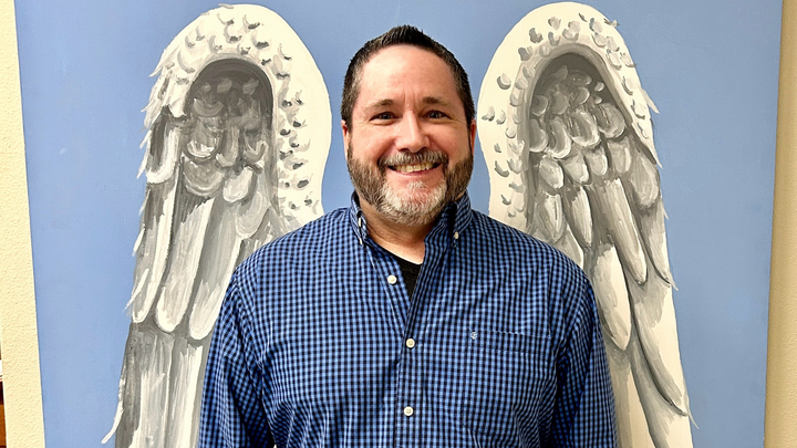 A generic middle aged white man in front of angel wings
