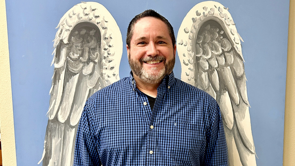 A generic middle aged white man in front of angel wings